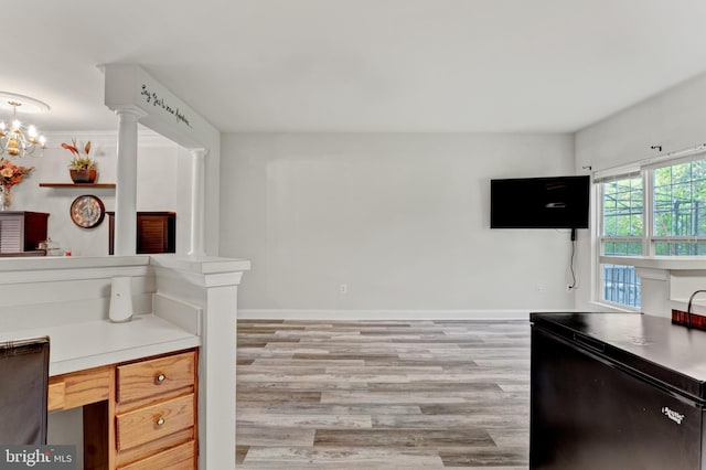 kitchen featuring light countertops, baseboards, decorative columns, and light wood-style flooring