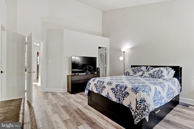 bedroom featuring baseboards, a high ceiling, and wood finished floors