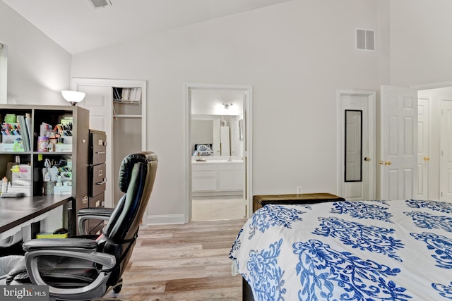 bedroom featuring high vaulted ceiling, light wood-style flooring, baseboards, ensuite bathroom, and visible vents