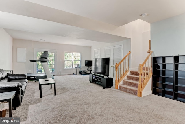 carpeted living area featuring baseboards and stairway