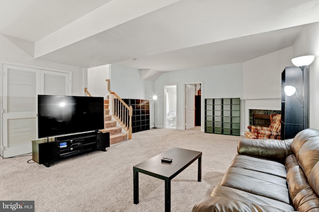 carpeted living room featuring a high end fireplace and stairway