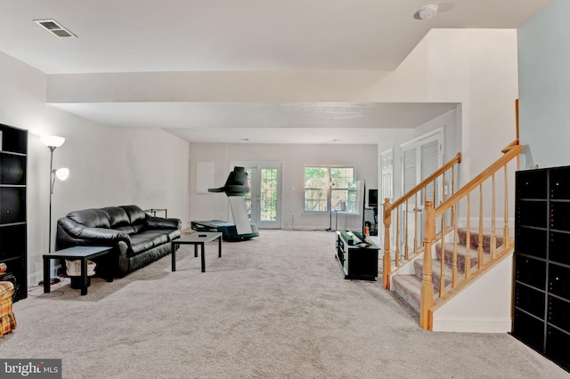 living room with carpet floors, baseboards, visible vents, and stairway