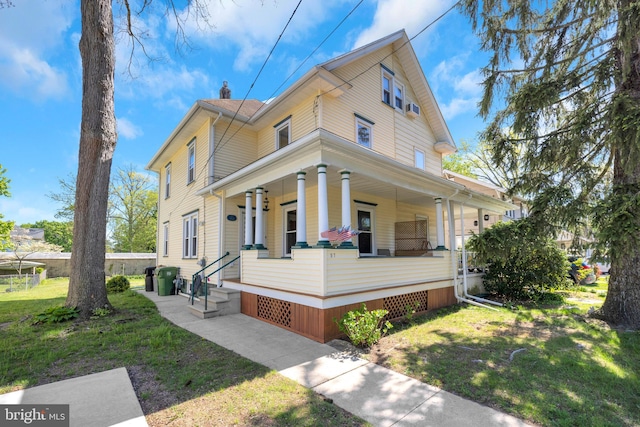 view of front of property featuring a porch, a chimney, and a front yard