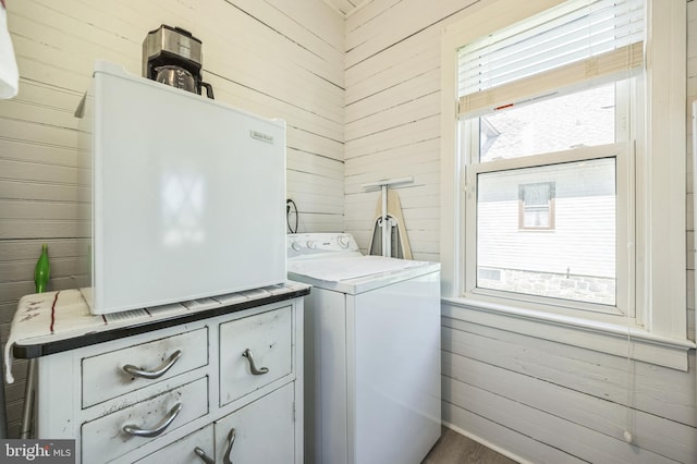 laundry room featuring wood walls, washer / dryer, and cabinet space