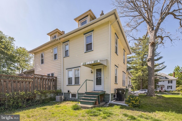 rear view of property with central AC unit, fence, a yard, and a chimney