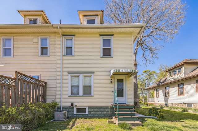 rear view of house with a lawn, central AC, and fence