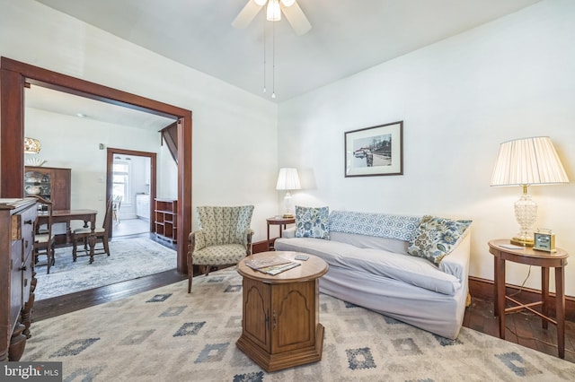 living room featuring baseboards, ceiling fan, and wood finished floors