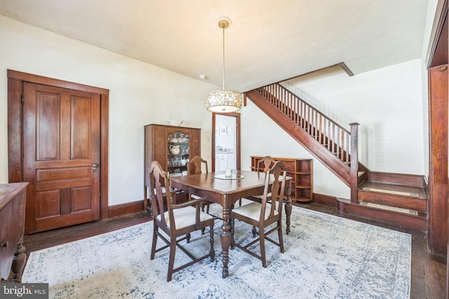 dining area featuring baseboards, wood finished floors, and stairway