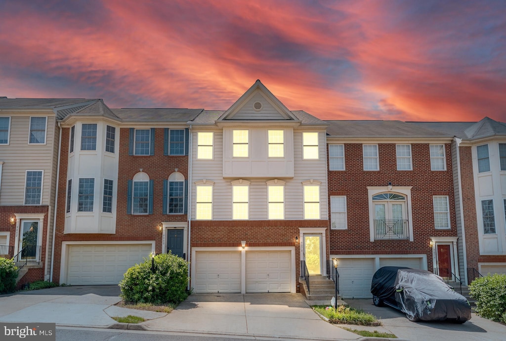 view of property featuring brick siding, driveway, and a garage