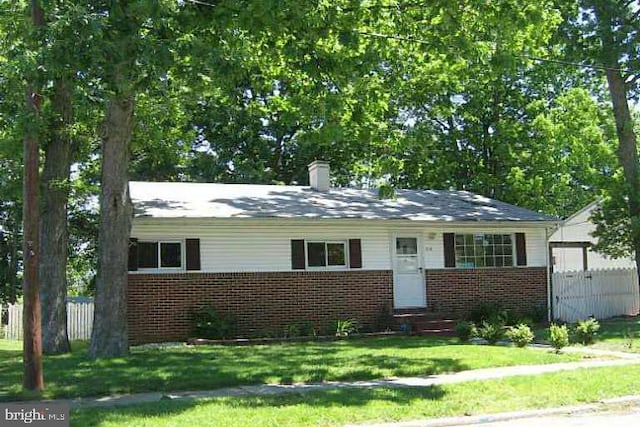 view of front of property featuring fence, a chimney, and brick siding