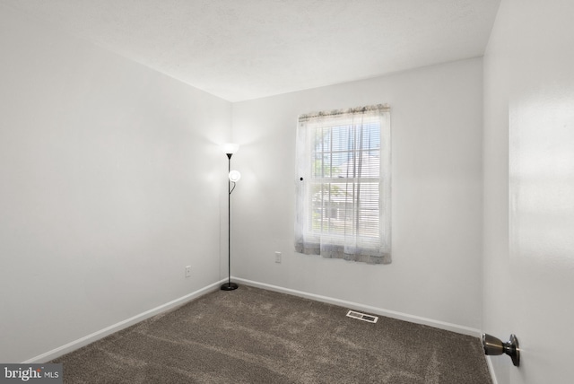 carpeted empty room featuring baseboards and visible vents