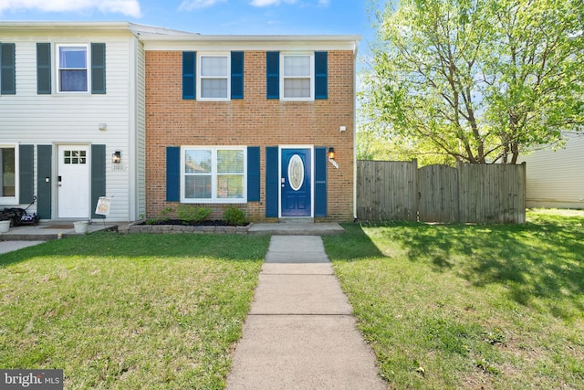townhome / multi-family property with brick siding, fence, and a front yard