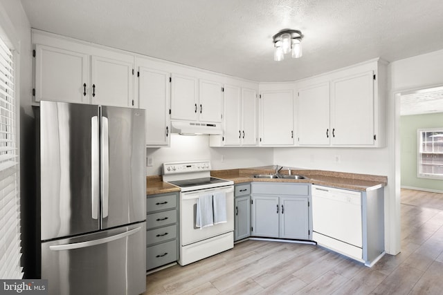 kitchen featuring light wood-style floors, white cabinets, under cabinet range hood, and white appliances