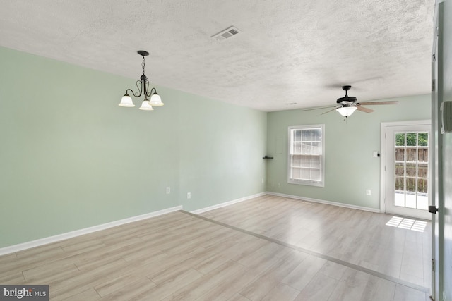 empty room featuring visible vents, baseboards, a textured ceiling, light wood finished floors, and ceiling fan with notable chandelier