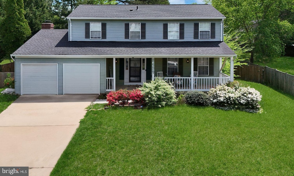 traditional home with a front lawn, fence, a chimney, concrete driveway, and a porch