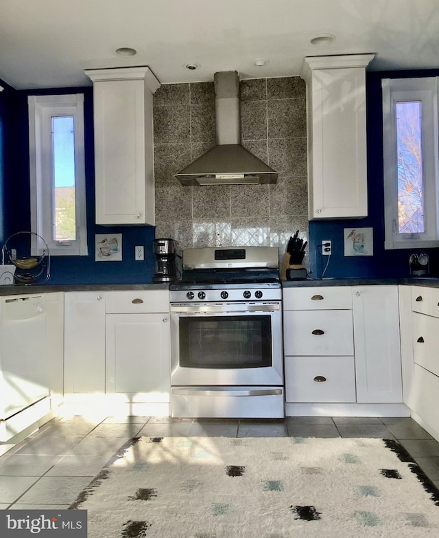 kitchen with tile patterned floors, stainless steel range with gas cooktop, wall chimney exhaust hood, and white cabinetry