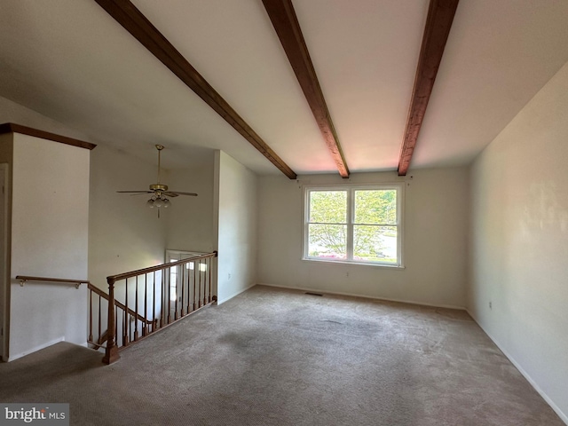 unfurnished room featuring a ceiling fan, beamed ceiling, and carpet flooring