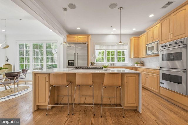 kitchen featuring built in appliances, visible vents, light wood-style flooring, and light brown cabinets