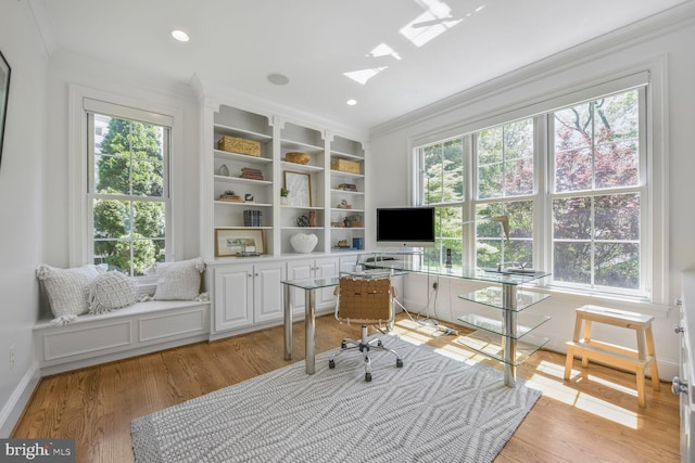 home office featuring crown molding, baseboards, a skylight, and light wood-style floors