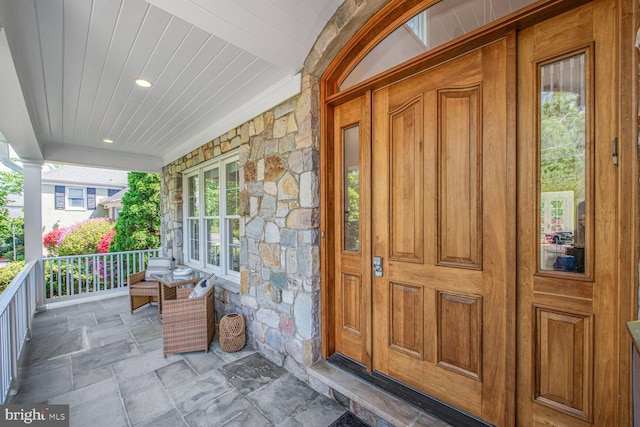 view of exterior entry with covered porch and stone siding