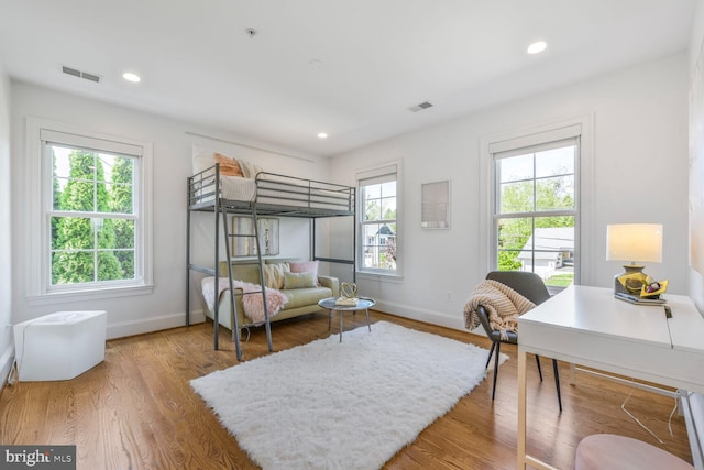 bedroom with visible vents, baseboards, and wood finished floors