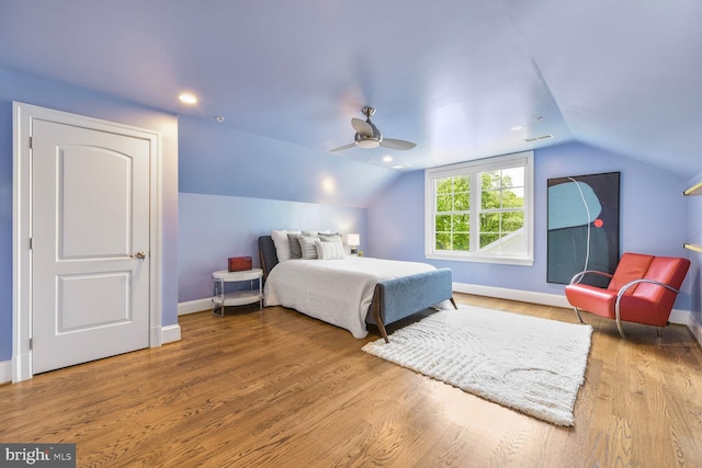 bedroom with a ceiling fan, visible vents, vaulted ceiling, wood finished floors, and baseboards