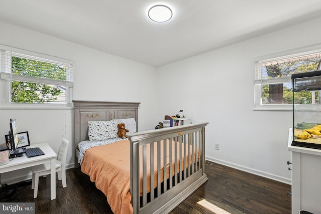 bedroom with baseboards, wood finished floors, and multiple windows