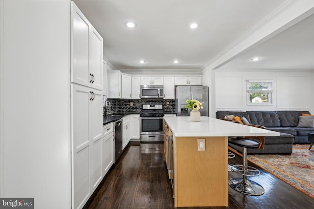 kitchen featuring a kitchen island, a breakfast bar, open floor plan, dark wood finished floors, and stainless steel appliances