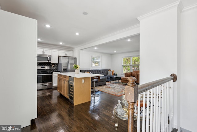 kitchen featuring crown molding, a kitchen island, beverage cooler, a kitchen bar, and stainless steel appliances