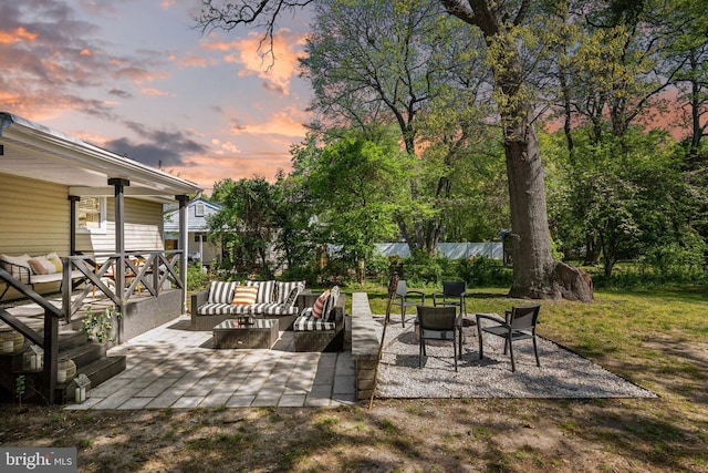 deck at dusk featuring a lawn, outdoor lounge area, and a patio area