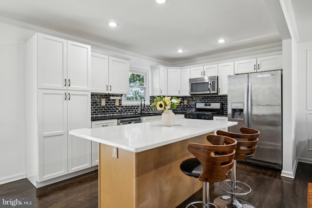kitchen with crown molding, a center island, dark wood-style floors, and stainless steel appliances