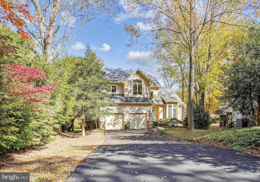 view of front facade with an attached garage, cooling unit, and driveway