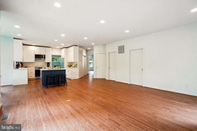 1145 Water Pointe Ln, Reston, VA 20194 - kitchen featuring appliances with stainless steel finishes, light wood finished floors, white cabinets, light countertops, and a kitchen island