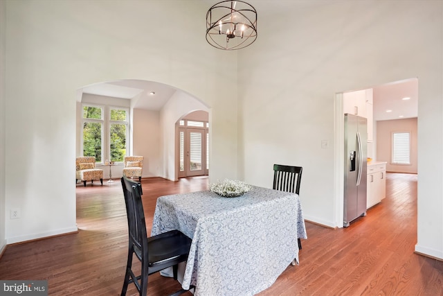 1145 Water Pointe Ln, Reston, VA 20194 - dining room with arched walkways, wood finished floors, a chandelier, a high ceiling, and baseboards