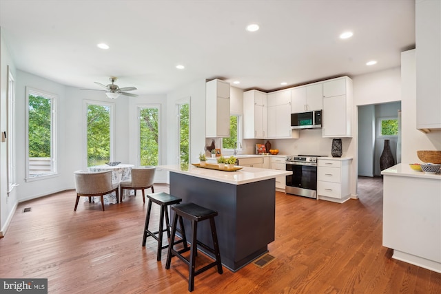 1145 Water Pointe Ln, Reston, VA 20194 - kitchen featuring appliances with stainless steel finishes, plenty of natural light, a kitchen breakfast bar, white cabinets, and recessed lighting