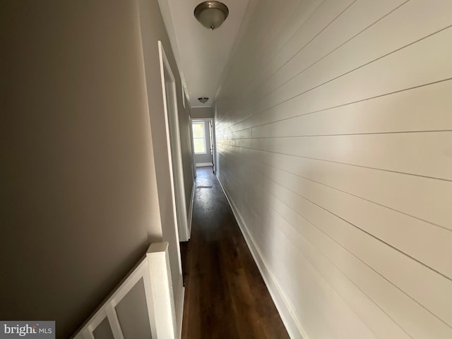 hallway with wooden walls and dark wood-style floors