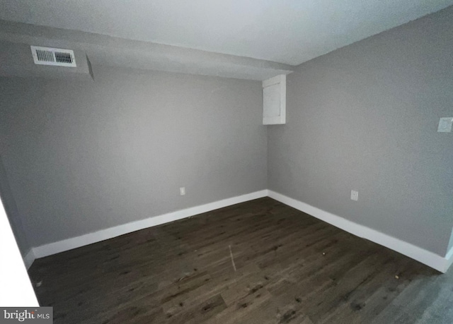 finished basement with visible vents, dark wood-style flooring, and baseboards