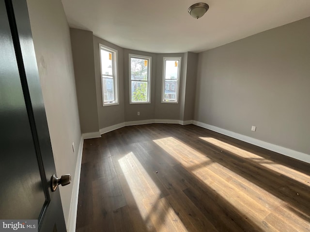 empty room with baseboards and dark wood-style floors