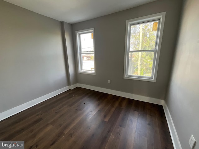 spare room featuring baseboards and dark wood finished floors