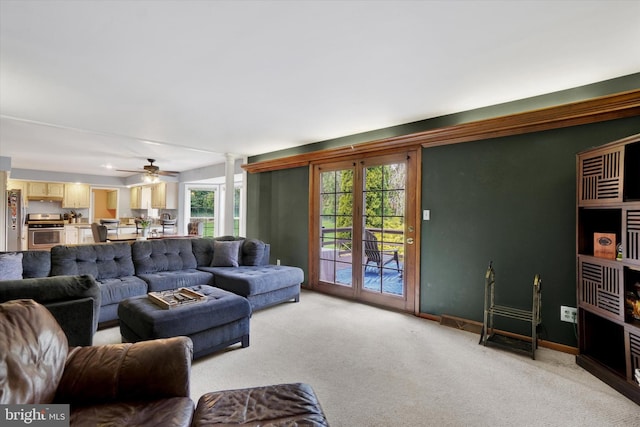 living room with baseboards, light carpet, and ceiling fan