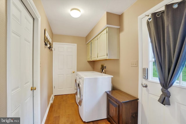 laundry area with light wood-style floors, cabinet space, baseboards, and washer and dryer