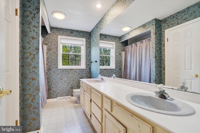 bathroom with baseboards, a sink, toilet, and wallpapered walls