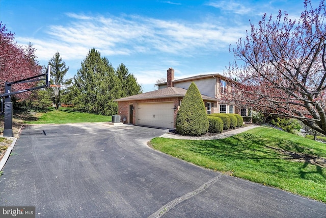 view of side of home with a yard, brick siding, an attached garage, and aphalt driveway