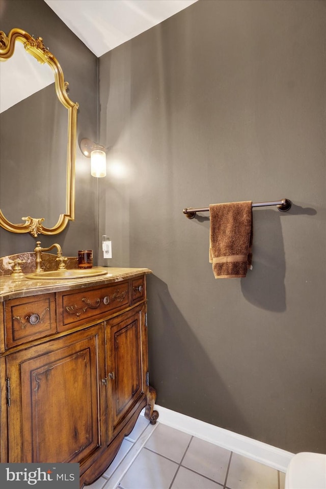 half bathroom featuring baseboards, tile patterned flooring, and vanity