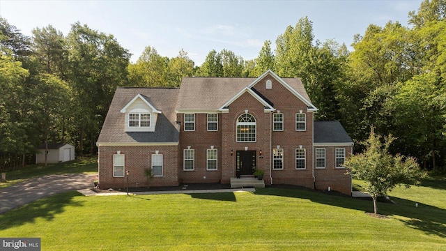 view of front of property with a storage shed, a front lawn, an outdoor structure, and brick siding