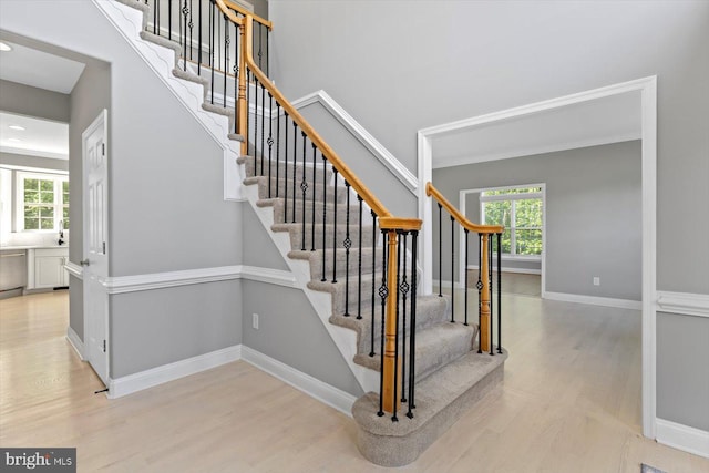 staircase with wood finished floors, healthy amount of natural light, baseboards, and recessed lighting