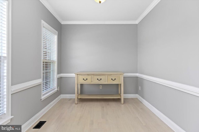 spare room with light wood-type flooring, crown molding, and baseboards