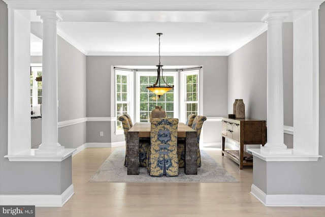 dining area featuring ornamental molding, light wood-style floors, baseboards, and decorative columns