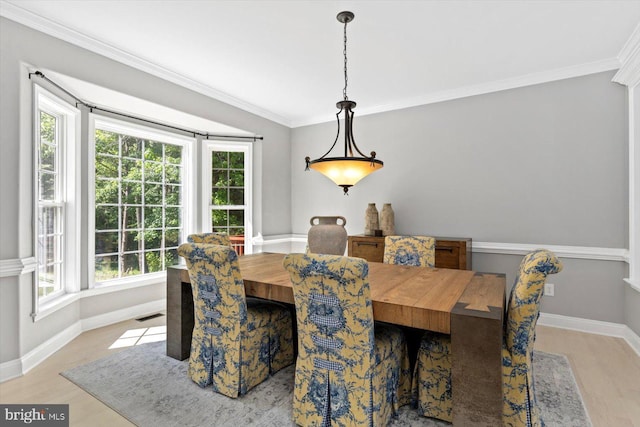 dining room with light wood finished floors, baseboards, and ornamental molding