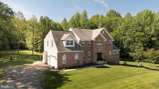 back of property with an attached garage, driveway, brick siding, and a lawn